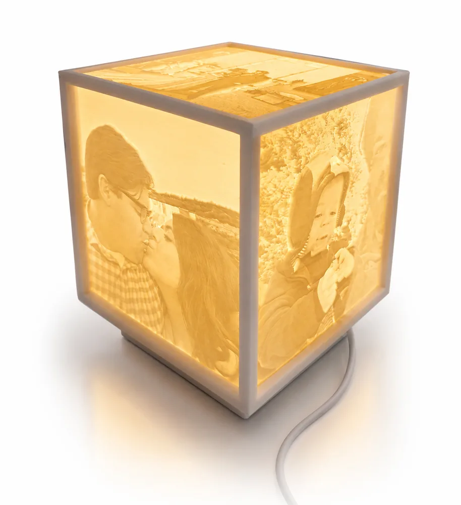 A lit Memorial Lantern: a cube whose faces each glow with a different photograph